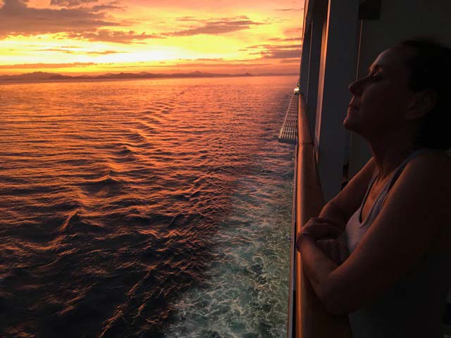 Photo of Nancy Phillips enjoying a beautiful sunset while on an ocean cruise.